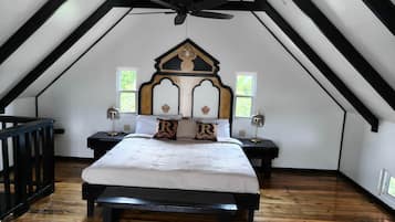 Une chambre avec un plafond en pente, un lit avec une literie blanche, deux tables de chevet avec des lampes et un banc en bois.