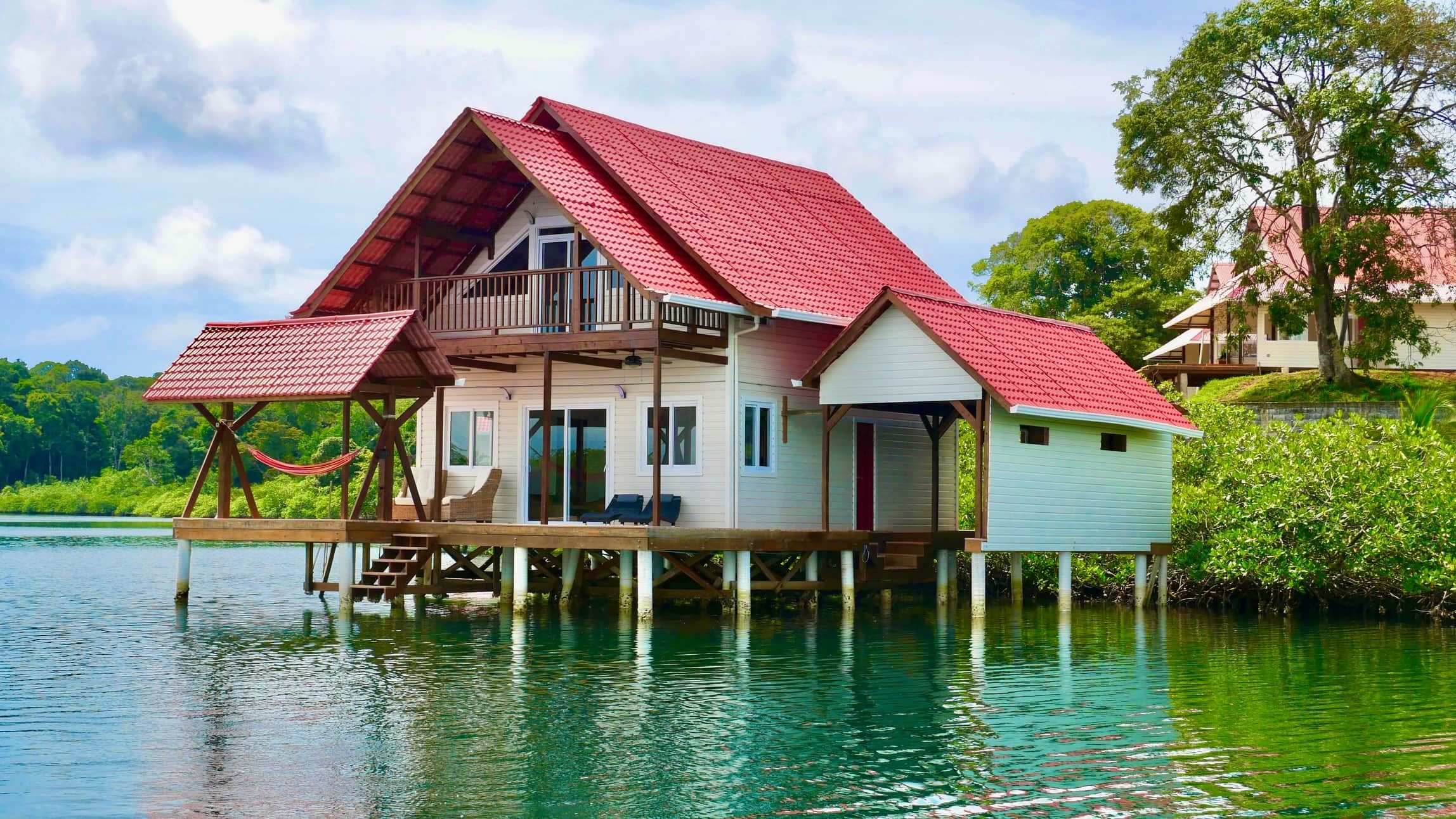Une maison avec un toit rouge, un balcon et une vue sur l’eau.