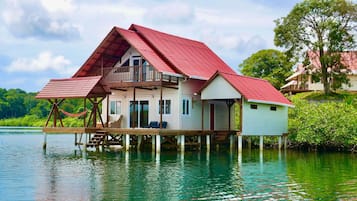 A house with a red roof, a balcony, and a view of the water.