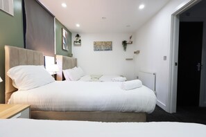 A hotel room with a large bed, bedside tables, a radiator, and a door to the right. - Stylish and comfortable apartment in Cardiff (Cardiff)