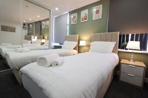 Habitació d'hotel amb dos llits, un mirall gran i obres d'art a les parets.