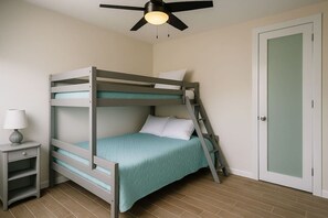 A bunk bed with a ladder, a bedside table with a lamp, and a door with a frosted glass panel. - Costa Córcega 5A | Beachfront, Pool & Beach Access (Rincón)