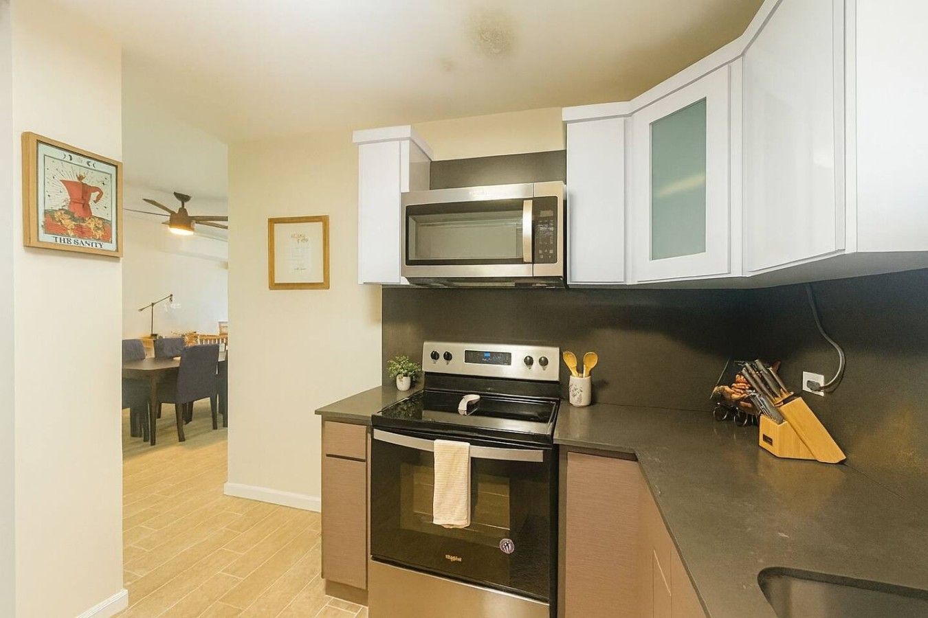 A compact kitchen with a microwave, oven, and stove. There is a dining area visible in the background.