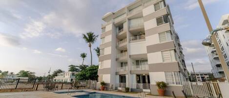 A multi-story residential building with a swimming pool and outdoor seating.