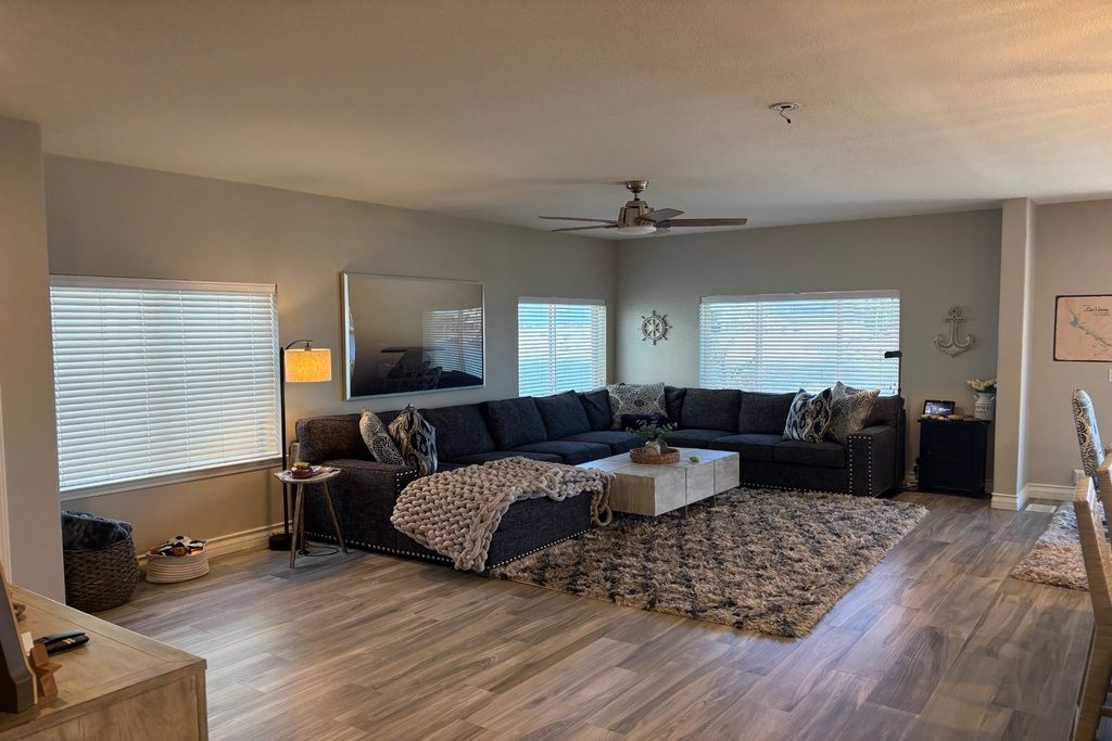 A living room with a dark-colored sofa, a coffee table, a rug, and a ceiling fan.