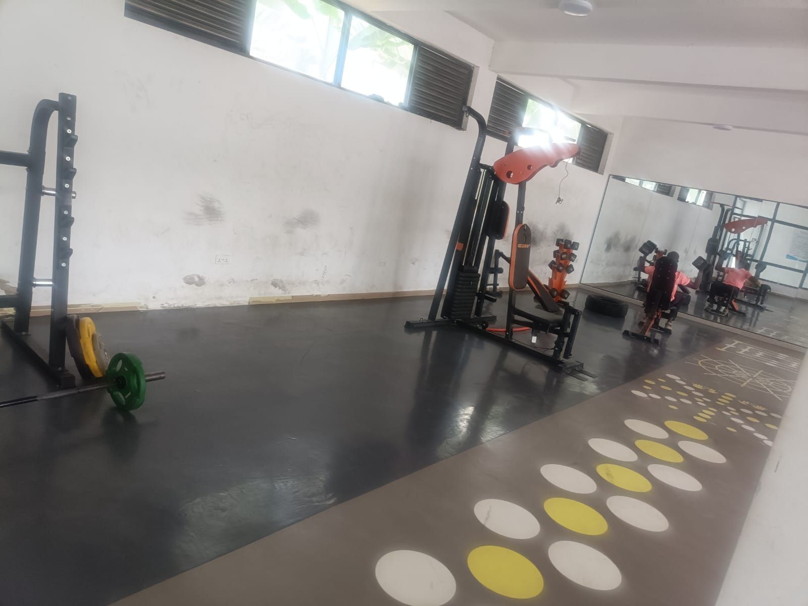 Un gimnasio con varios equipos de ejercicio, incluyendo un rack de sentadillas y una prensa de banca.