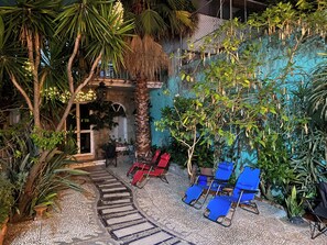 An outdoor patio area with a stone pathway leading to a seating area with blue chairs. - HOSTEL & LOFTS CASA LUMA (Guadalajara)