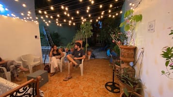 A covered outdoor seating area with string lights, potted plants, and a sign indicating a rest area.