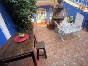 A patio area with a wooden table, a bench, and potted plants. - HOSTEL & LOFTS CASA LUMA (Guadalajara)