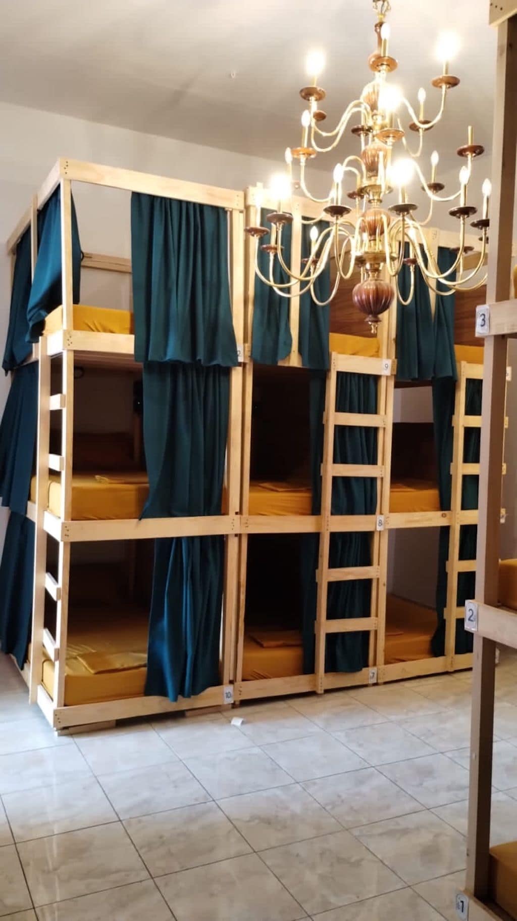 A bunk bed room with a chandelier, curtains, and numbered storage units.