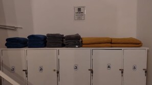 A row of lockers with folded towels in blue, gray, and mustard colors. - HOSTEL & LOFTS CASA LUMA (Guadalajara)