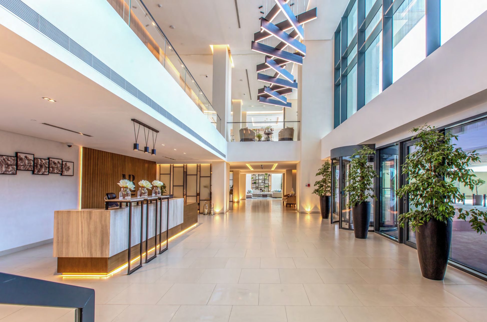 Un hall d’entrée spacieux et moderne, doté d’un comptoir de réception, d’un espace salon et de grandes fenêtres.