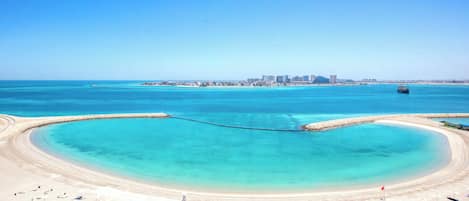 A coastal beach with a clear view of a city skyline in the background.