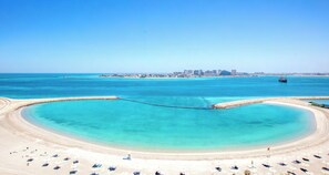 A coastal beach with a clear view of a city skyline in the background. - Delightful 2-bedroom apartment with AC in Marassi (Muharraq Governorate)