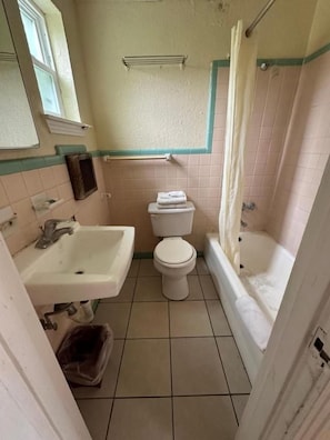 A bathroom with a sink, toilet, bathtub, and shower curtain. - Sands Motel (San Antonio)