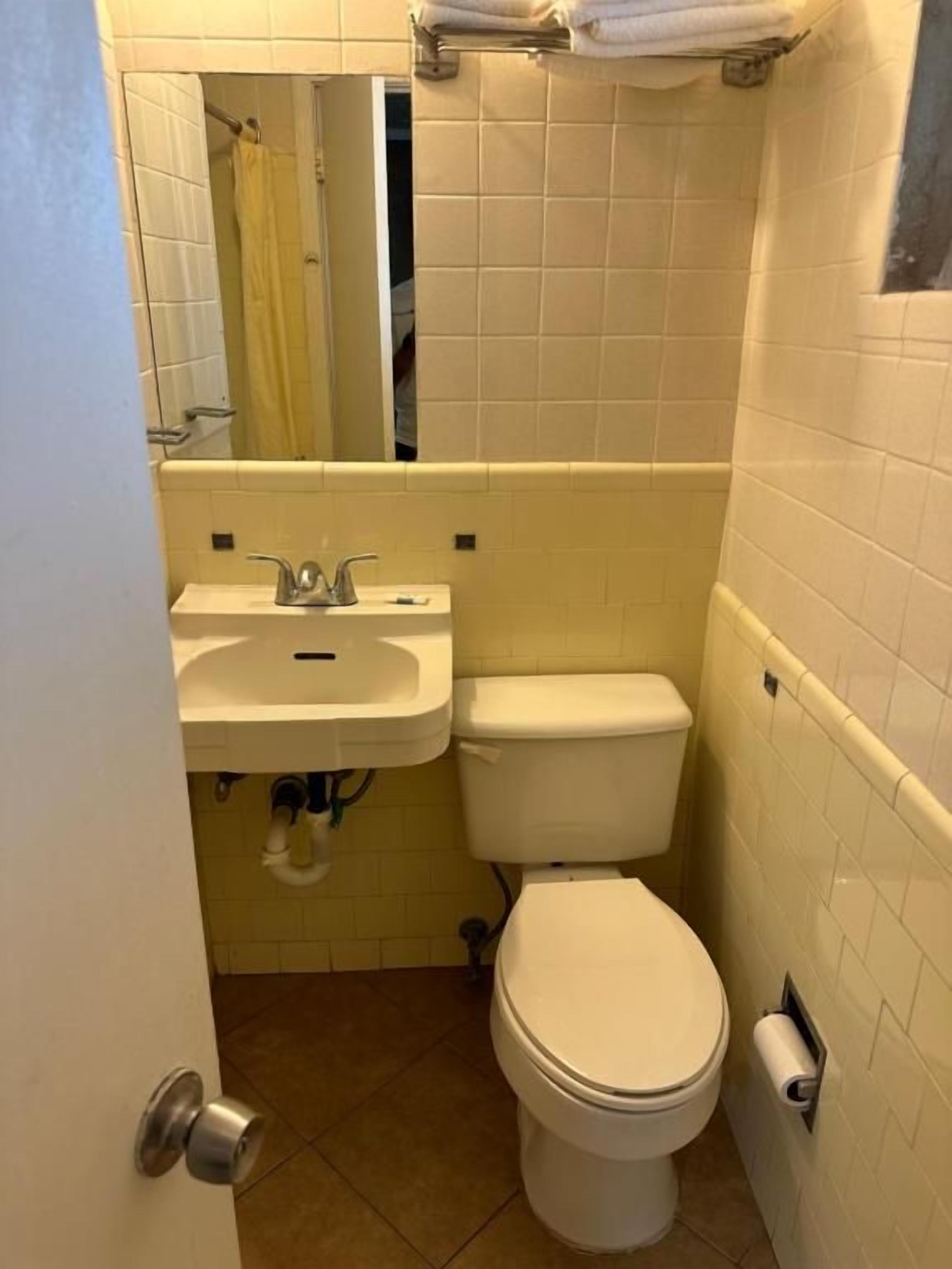 Une petite salle de bain avec des toilettes, un lavabo et un miroir.