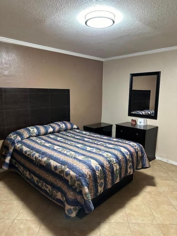 Un dormitorio con cama, mesita de noche, cómoda, espejo y lámpara de techo.