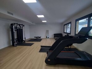 A gym with a treadmill, weight machines, and exercise mats. - Modern Luxury Penthouse with Private Rooftop Terrace & Pool Access (Los Almendros)