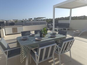 A rooftop terrace with a checkered table set for dining, surrounded by white chairs, and a view of the cityscape. - Modern Luxury Penthouse with Private Rooftop Terrace & Pool Access (Los Almendros)