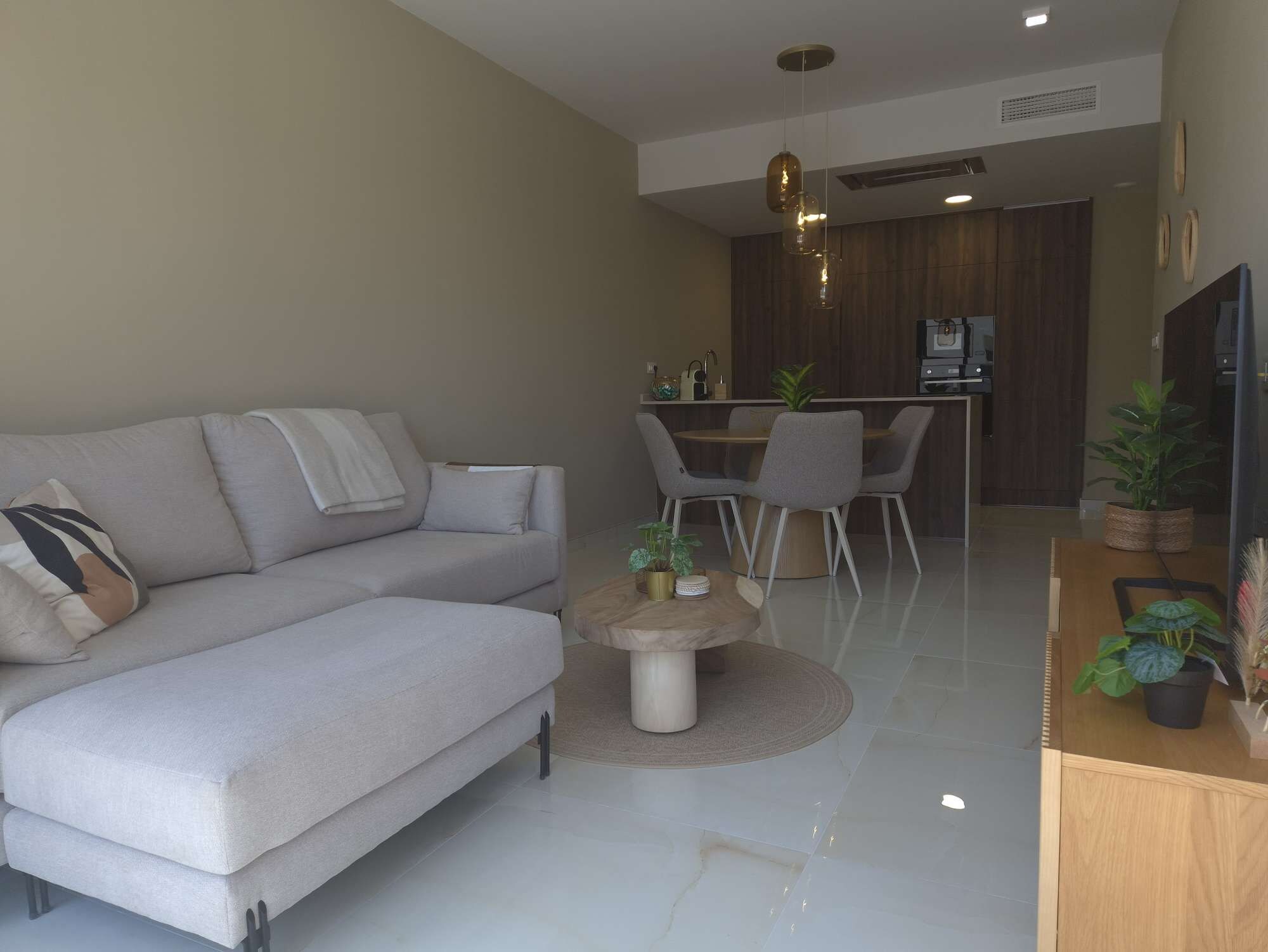 Uma sala de estar moderna com sofá, mesa de centro e área de jantar com cadeiras e mesa.