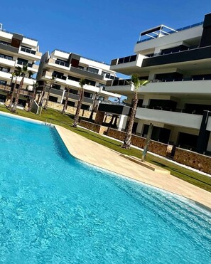 A modern multi-story hotel with a swimming pool. - Modern Luxury Penthouse with Private Rooftop Terrace & Pool Access (Los Almendros)