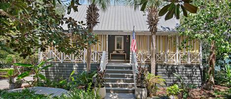 A house with a porch, steps leading to the entrance, and a flag.