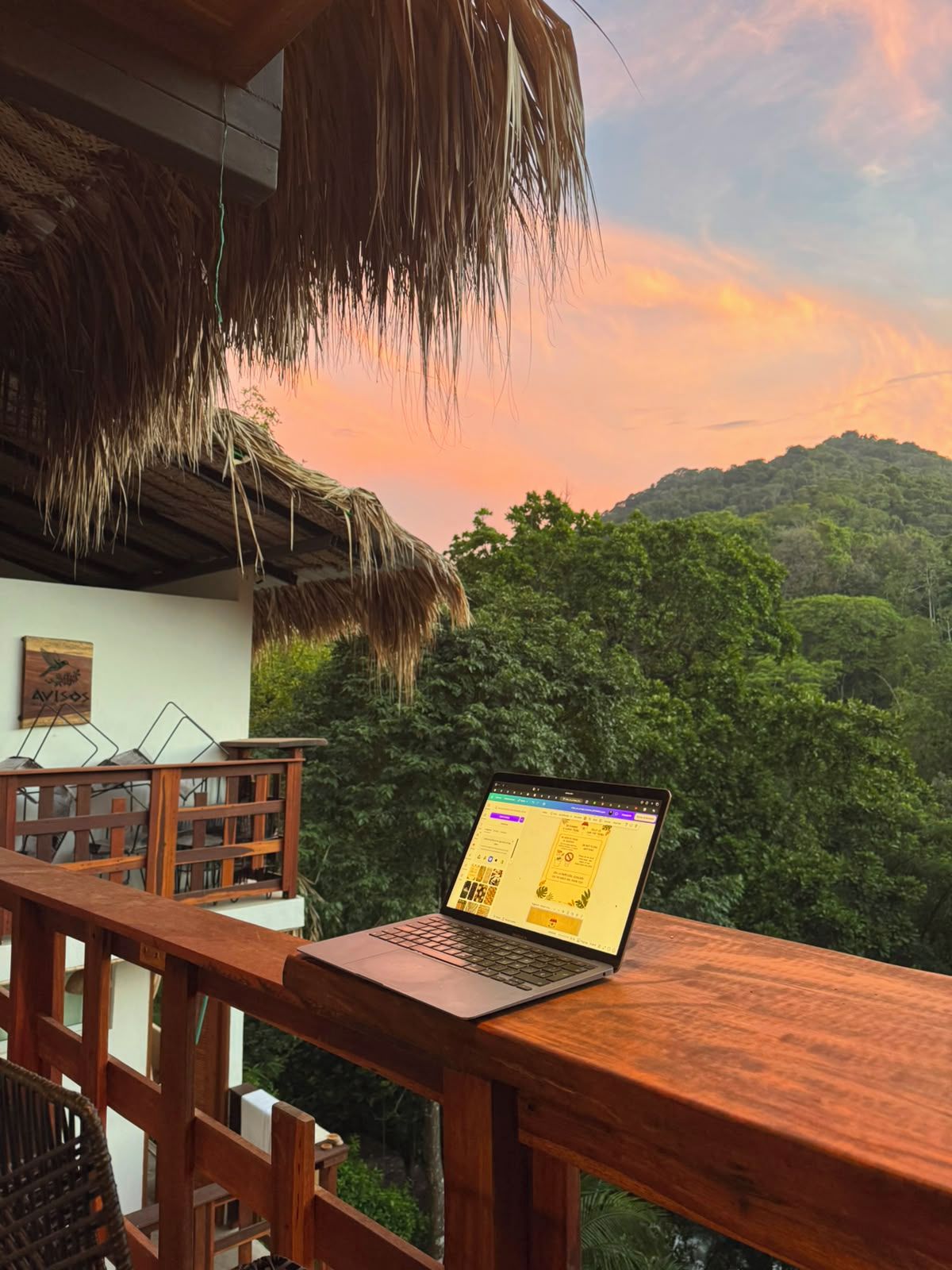 Um laptop sobre uma mesa de madeira, com vista para uma montanha arborizada ao fundo.