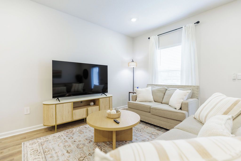 A modern living room with a flat-screen TV, a sofa, a coffee table, and a floor lamp.