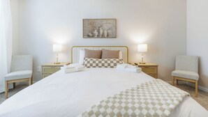 Una habitación de hotel con una cama grande, dos lámparas de noche, un cuadro en la pared y dos sillas.