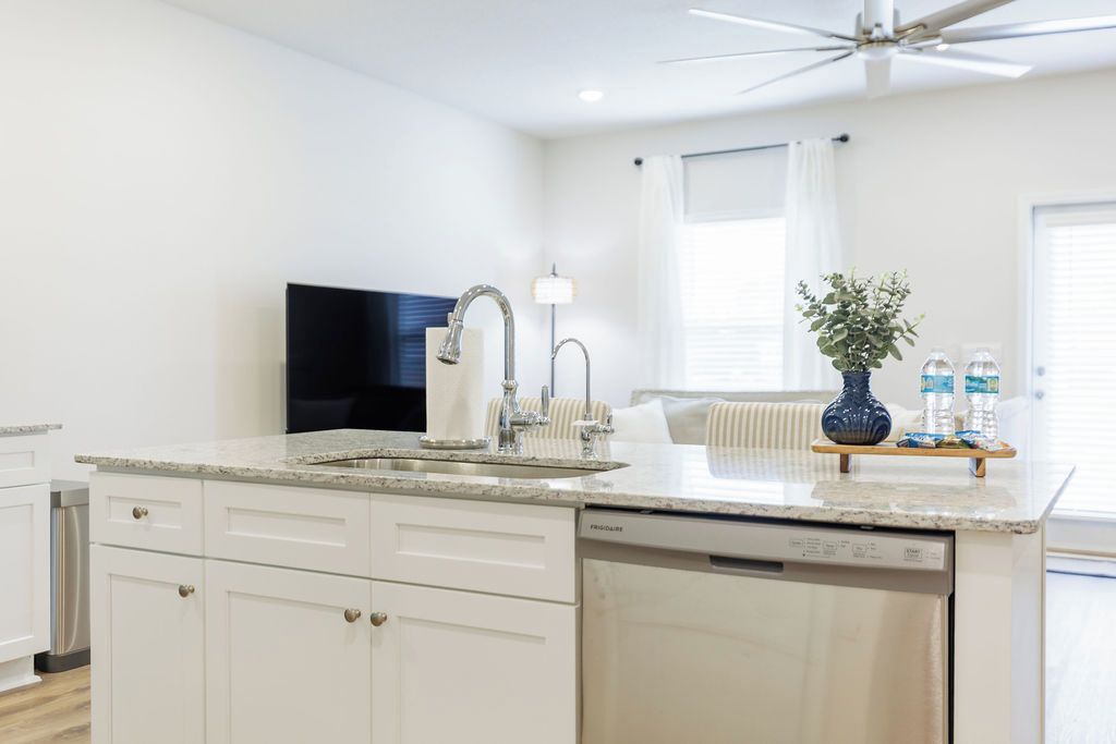 A modern kitchen with a built-in dishwasher, a large island with a sink, and a ceiling fan.