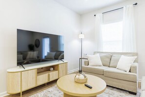 A living room with a flat-screen TV, a round coffee table, a sofa, and a floor lamp.