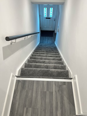 A staircase with a handrail, carpeted steps, and a wooden floor. - 3 Bedroom Full House (Ashington)