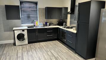 Una cocina moderna con lavadora integrada, microondas y refrigerador de acero inoxidable.