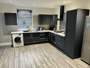 A modern kitchen with a built-in washer, a microwave, and a stainless steel refrigerator. - 3 Bedroom Full House (Ashington)