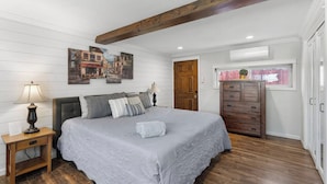 Un dormitorio con cama, mesitas de noche, cómoda y viga de madera en el techo.