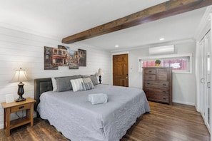 Un dormitorio con cama, mesitas de noche, cómoda y viga de madera en el techo.