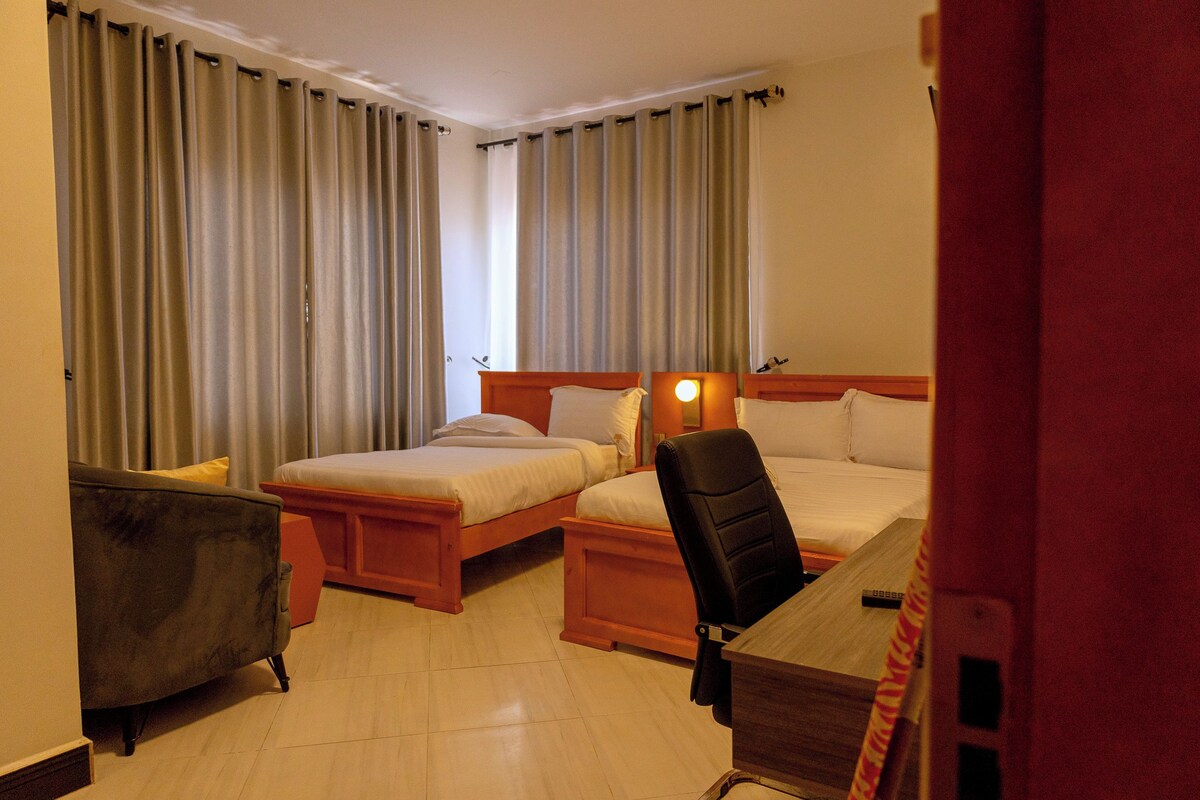 Ein Hotelzimmer mit zwei Betten, einem Schreibtisch, einem Stuhl und einem Kleiderschrank.