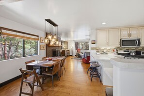 A spacious kitchen with a dining area, wooden flooring, and a view of the outdoors.