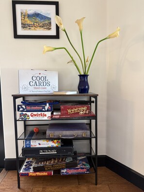 A shelf with various board games and a framed landscape painting.