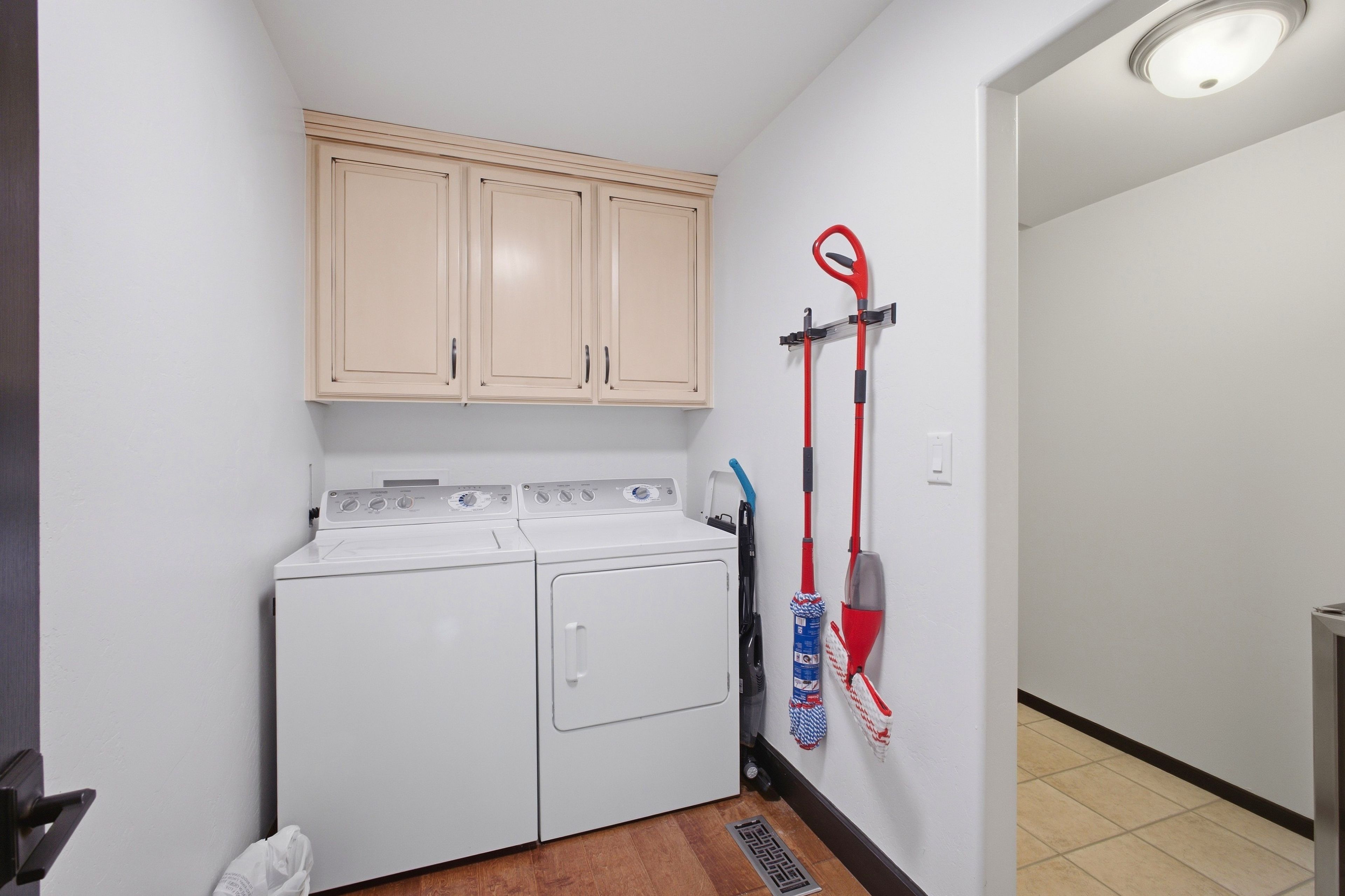 A laundry room with a washing machine, a drying rack, and a mop.