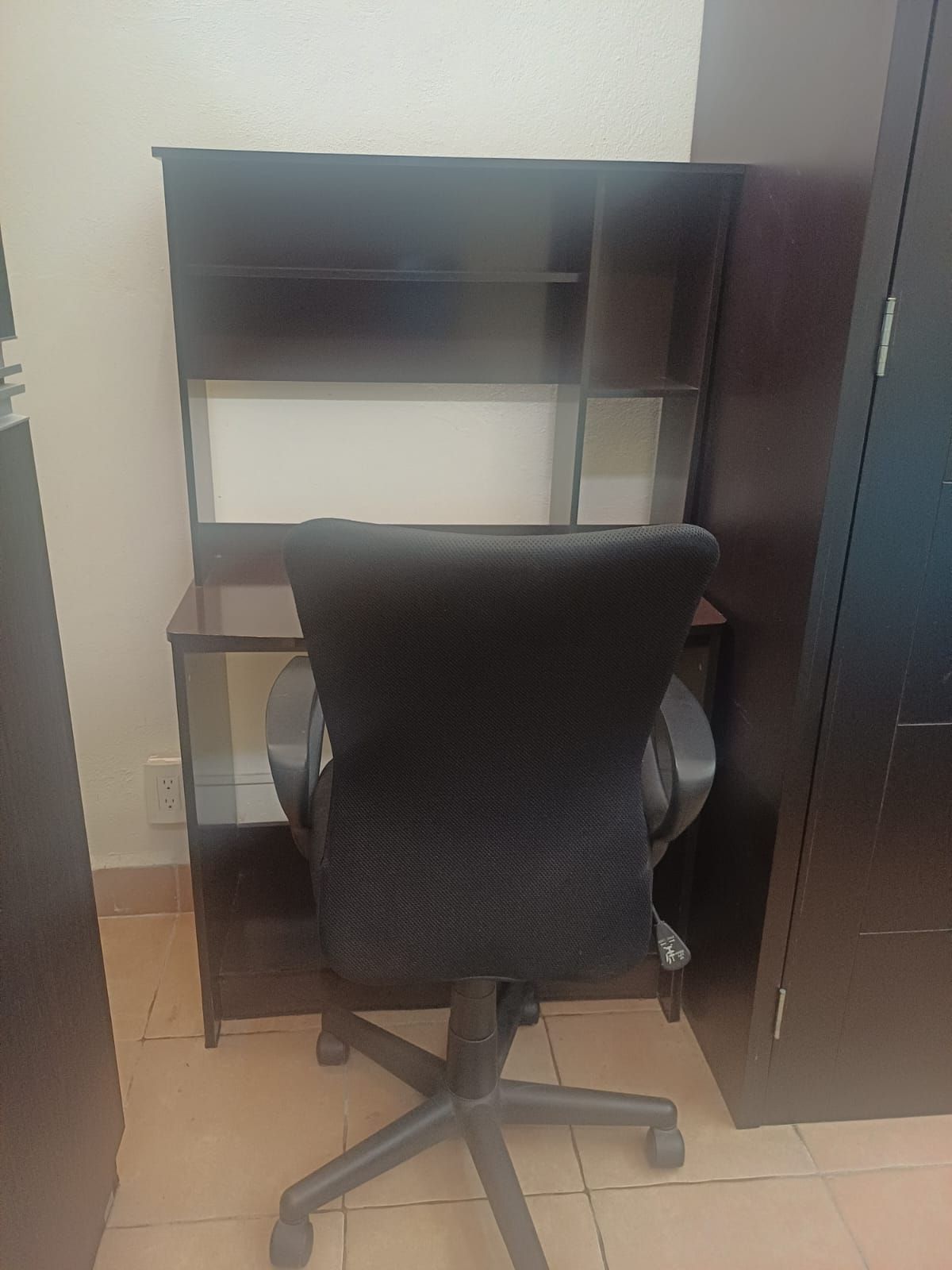 Een werkplek met een bureau, stoel en een plankensysteem.
