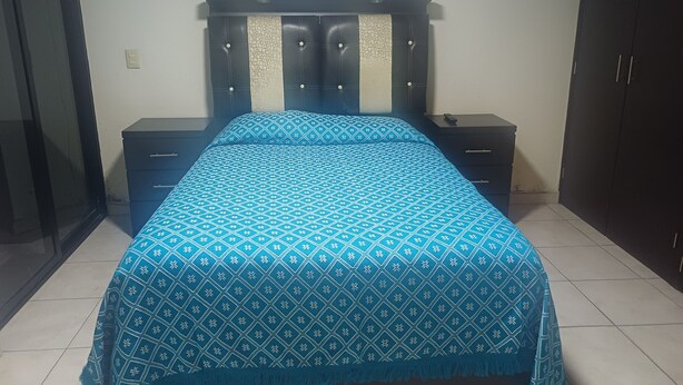 A bedroom with a bed, two bedside tables, a headboard, a wall-mounted artwork, and a wardrobe. - Loft para Turistas o Negocios (Toluca de Lerdo)