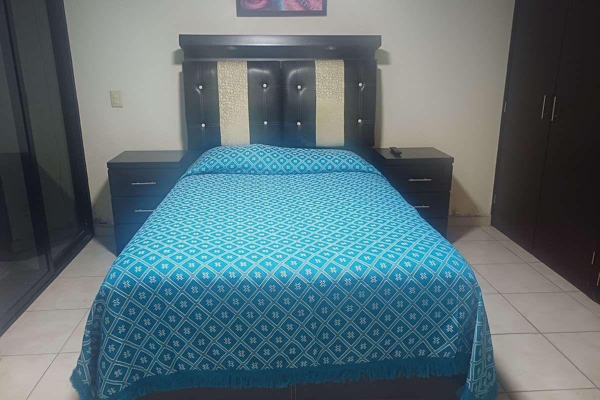 Un dormitorio con cama, dos mesitas de noche, cabecero, una obra de arte en la pared y armario.
