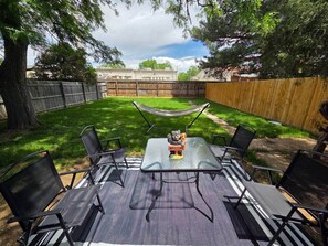 An outdoor patio with a table and chairs, surrounded by a wooden fence and trees. - West Campus Peaceful Paradise (Fort Collins)