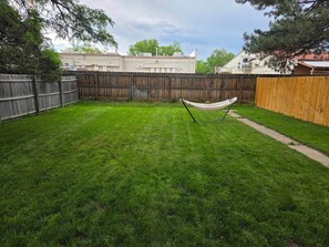 A backyard with a hammock, a wooden fence, and a grassy lawn. - West Campus Peaceful Paradise (Fort Collins)
