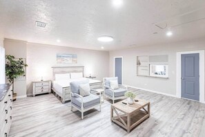 Ein geräumiges Zimmer mit einem Bett, zwei Sesseln, einem Couchtisch und einer Kommode.