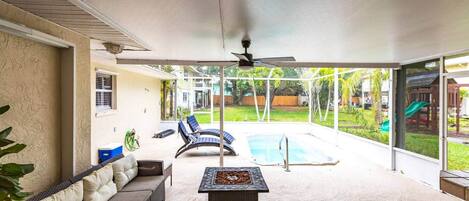 Un patio couvert avec une piscine, des chaises longues et une table.
