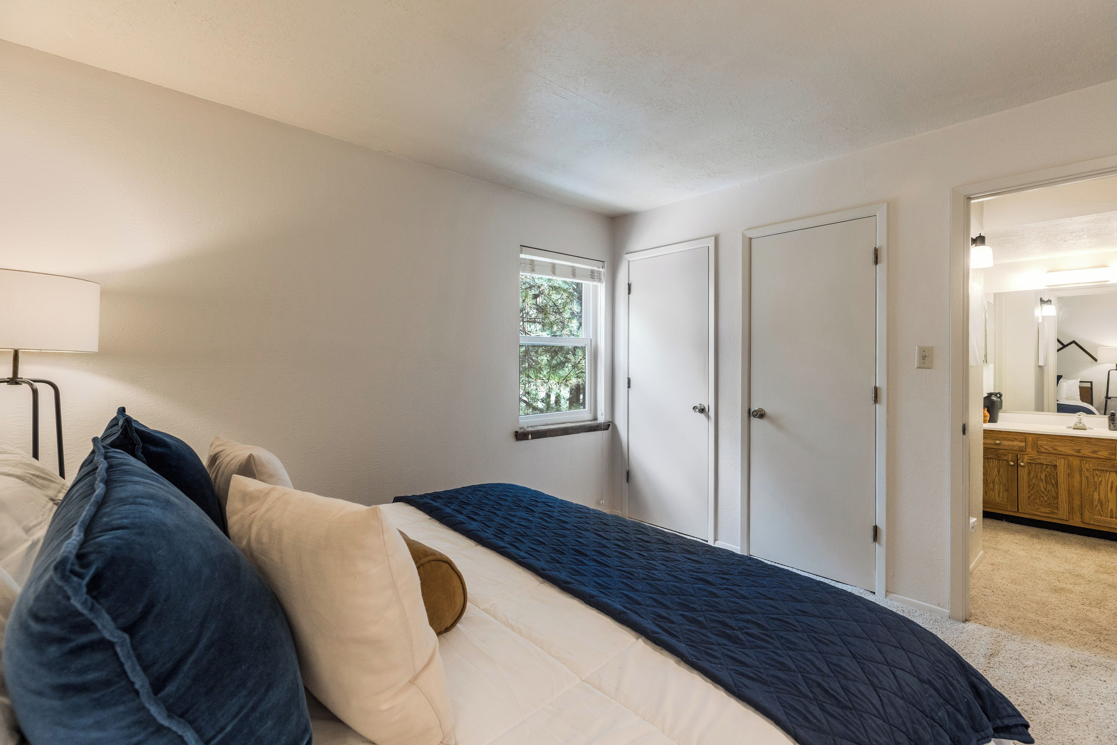Une chambre à coucher avec un lit, une fenêtre et une porte donnant sur une salle de bain.