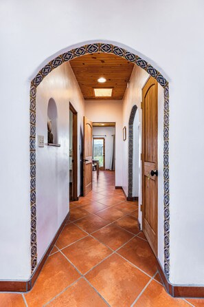 A hallway with a tiled floor, wooden doors, and patterned wall tiles.