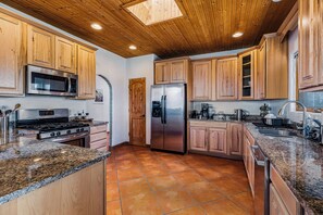 A kitchen with wooden cabinets, stainless steel appliances, and a tiled floor.